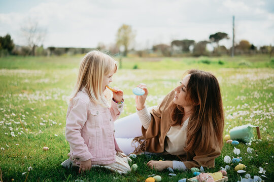 Mother and daughter relaxing in wildflower field after easter egg hunt, Arezzo, Tuscany, Italy