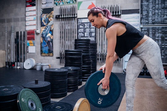 Young woman lifting weight plate in gym