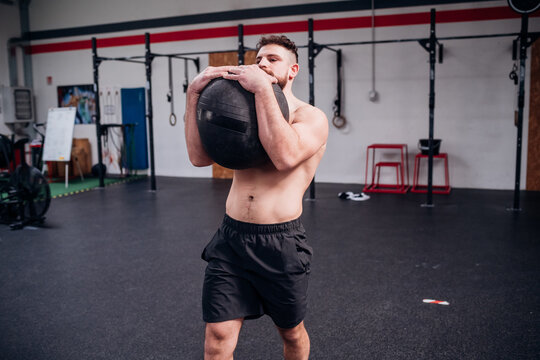 Young Man Training, Lifting Atlas Ball In Gym