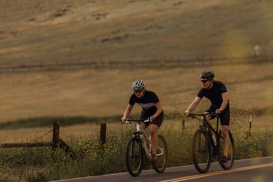 Young cycling couple cycling on rural road, Exeter, California, USA