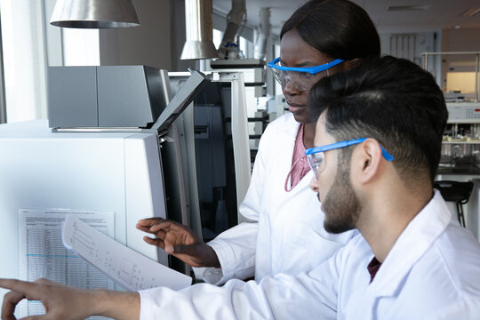 Young female and male scientists discussing paperwork in laboratory