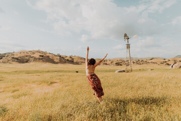 Young woman dancing in field landscape, rear view, Exeter, California, USA