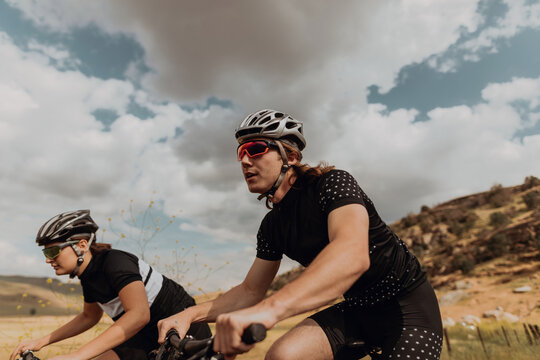 Young cycling couple cycling on rural road, side view, Exeter, California, USA