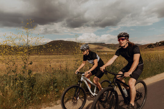 Young cycling couple cycling on rural road, Exeter, California, USA