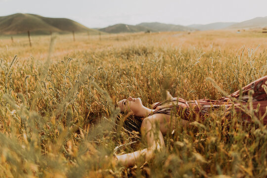 Young woman lying in field of long grass, Exeter, California, USA