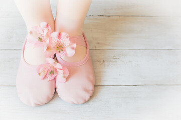 Little girl ballerinas feet in pink ballet shoes standing on a wooden surface , dancing concept, ballet