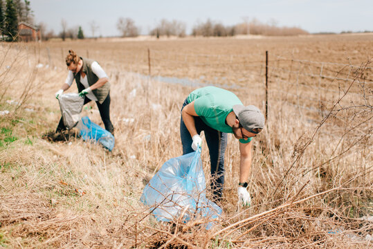 Couple picking up rubbish by field, Georgetown, Canada