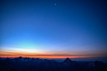 Orange glow on horizon over mountain range, Saas-Fee, Valais, Switzerland
