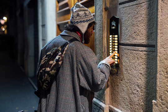 Bearded young man checking directory panel on wall of building
