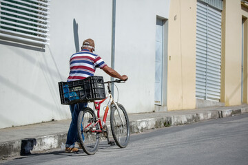 Homem empurrando bicicleta na rua com cesta de compras.