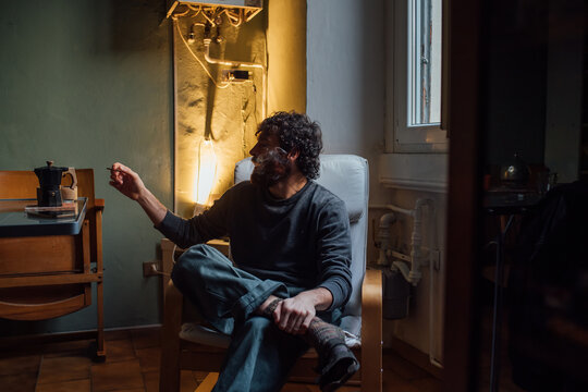 Bearded young man smoking at home