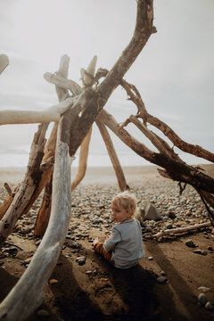 Toddler sitting inside wickiup on beach