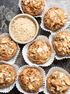 Still life of wholemeal muffins in cake cases with bowl of oats, overhead view