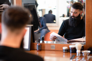 Customer waiting and reading in barber shop