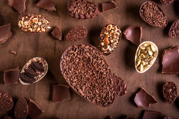 Top view of lots of mini stuffed chocolate easter eggs and cracked chocolates on a wooden table.