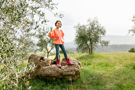 Cute girl with bobbed hair standing on rock in scenic field landscape, portrait, Citta della Pieve, Umbria, Italy