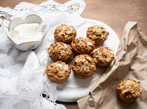 Still life of wholemeal muffins on plate with bowl of soft cheese, overhead view
