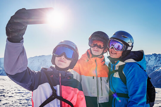 Skiers, mother with teenage son and daughter taking selfie on snow covered mountain top,  Alpe-d'Huez, Rhone-Alpes, France