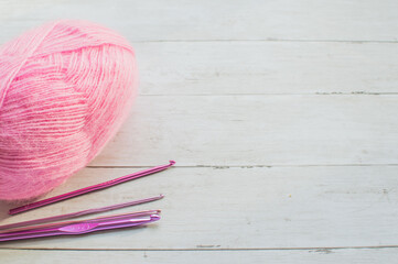 Colorful crocheting hooks and pink wool yarn 