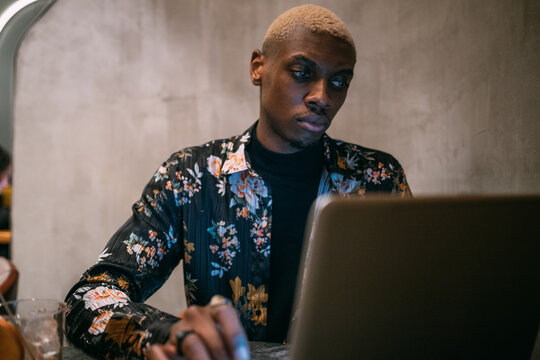 Stylish man using laptop, concrete wall background