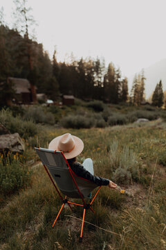 Young woman in stetson relaxing on deck chair in rural valley, rear view, Mineral King, California, USA