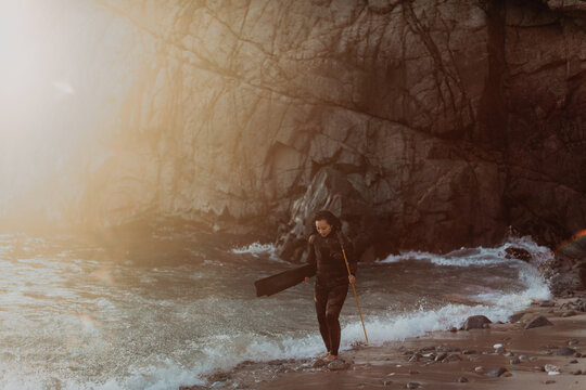 Woman with flippers and spear on beach, Big Sur, California, United States