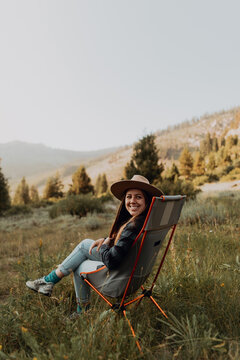 Young woman looking back from deck chair in rural valley, portrait, Mineral King, California, USA