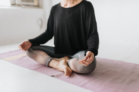 Woman sitting in lotus pose in yoga studio