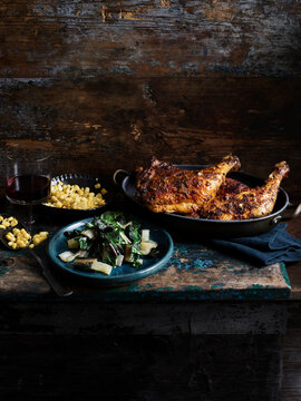 Rustic still life with chipotle chicken, corn and rainbow chard on wooden table