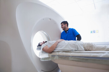 Young male radiographer operating CT scanner in radiology department