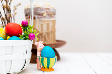 Easter background with basket full of colorful eggs, easter bunny and easter cake (aka: Orthodox sweet bread, kulich or Paska). Copy space for text. Wooden background.