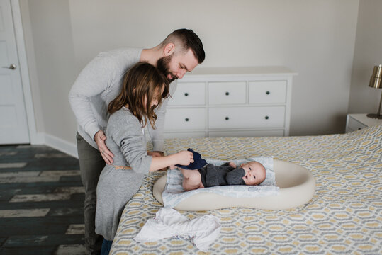 Girl with father changing baby brother's diaper on bed, side view