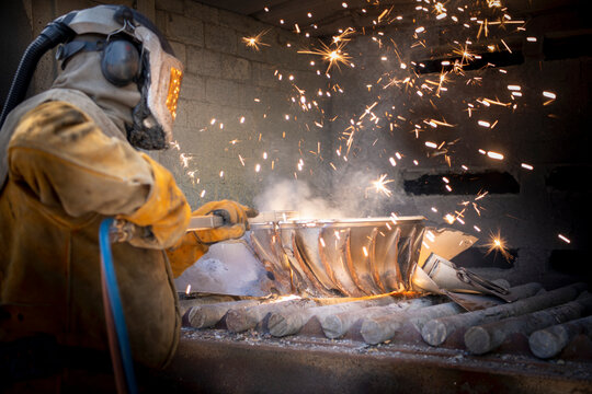 Worker cutting up scrap titanium aircraft parts in titanium recycling plant