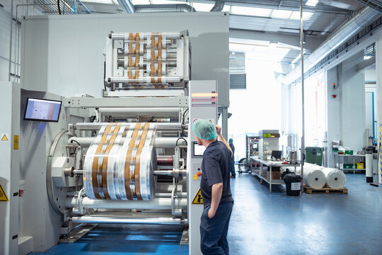 Worker with food packaging printing machine in print factory