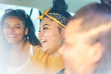 Young woman with teenage sisters in car back seat laughing, close up