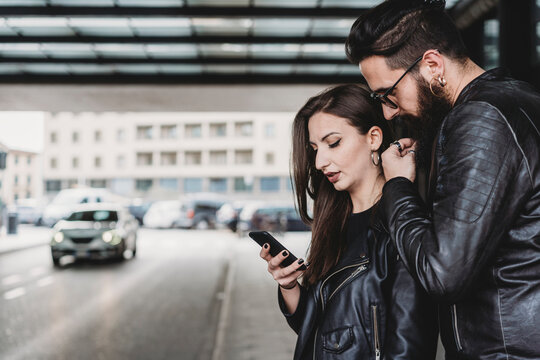 Couple using smartphone outside station