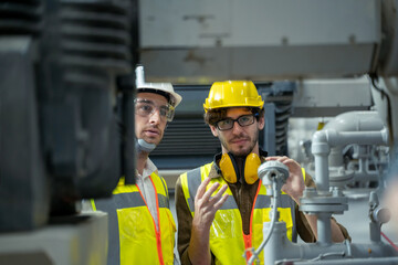 Industrial engineers discuss details with factory worker while using tablet computer working at heavy Industry Manufacturing Facility.