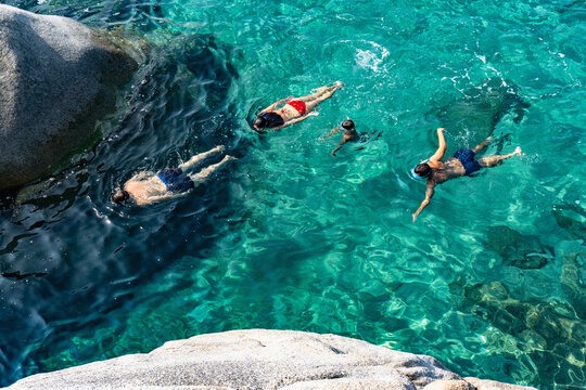 Family of four swimming in crystal clear sea, Cagliari, Sardinia