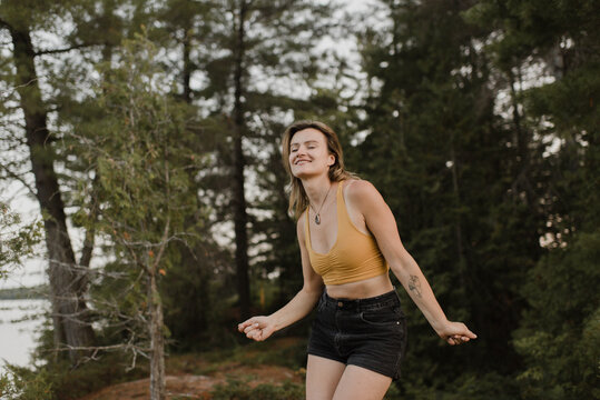 Woman dancing with eyes closed in forest