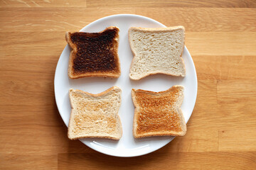 Four sliced bread on plate. Fresh, light toast, crispy toast and burnt