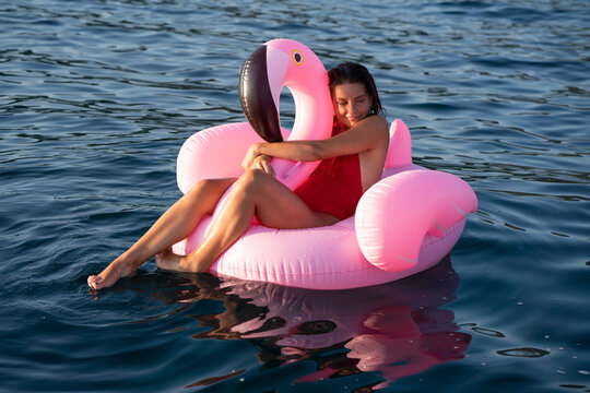 Woman on flamingo float on sea, Italy