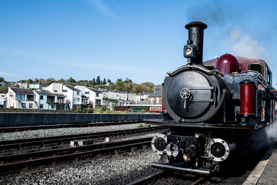 Steam train passing through town, Llanaber, Gwynedd, United Kingdom
