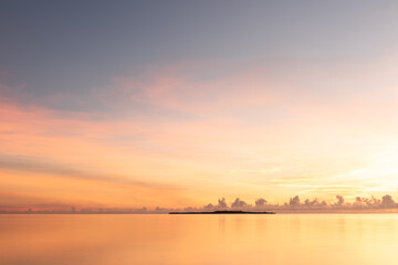 Fototapeta na wymiar Gorgeous serene sunrise, smooth sea, colorful pastel tones sky, Hatoma island in silhouette in the background. Iriomote Island.