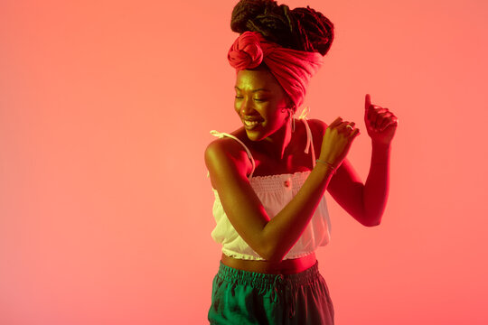 Woman with headscarf dancing against peach background