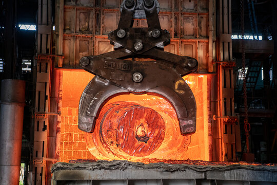  Heat treated red hot steel ingot being lifted by crane in furnace in steelworks