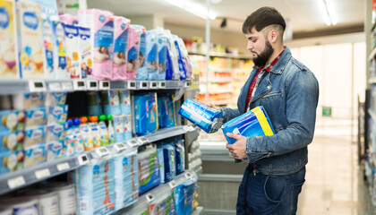 Interested young man looking for disposable nappies for newborns in store