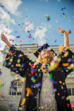 Graduating student throwing confetti into air at campus
