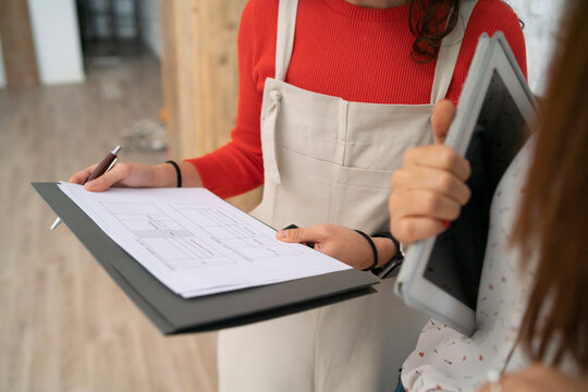 Two mid adult women checking plans in their new shop, mid section