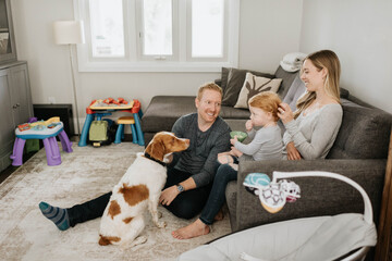 Family of three and pet dog relaxing in living room