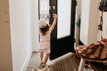 Toddler opening front door of house